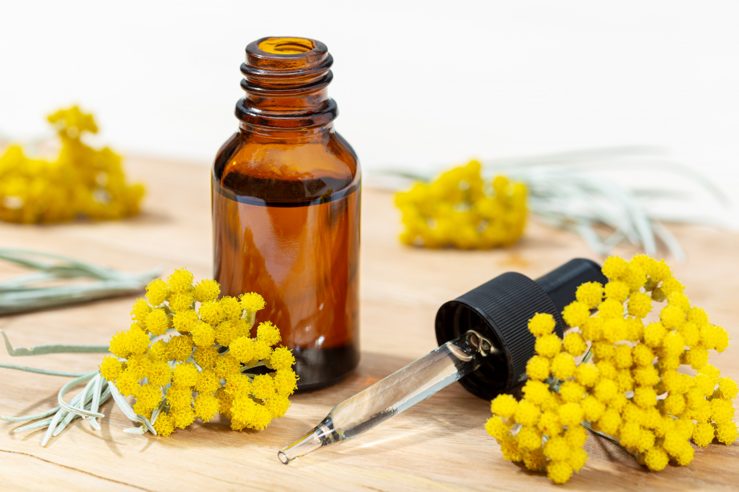 Ein Braunglasfläschchen und eine Pipette umgeben von gelben Blüten