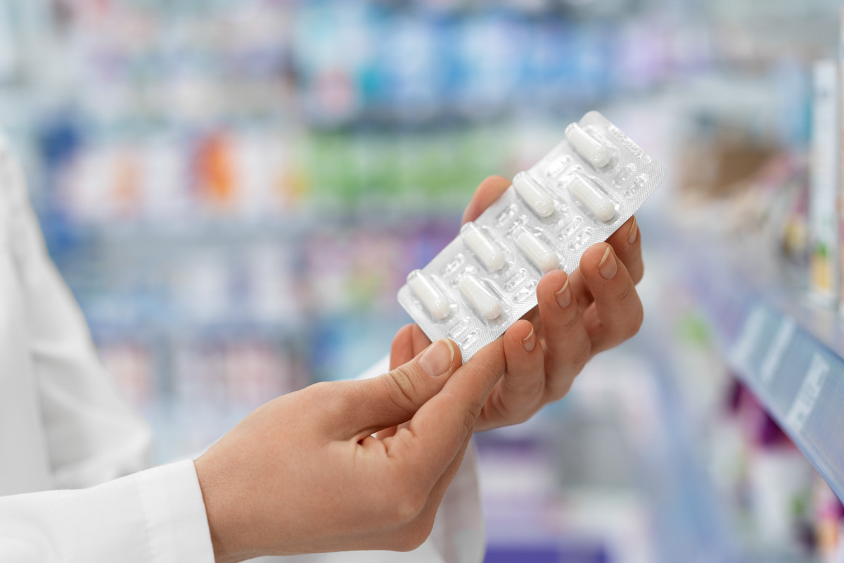 Apotheker hält eine Blisterpackung mit weißen Kapseln in der Hand